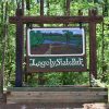 Hanging "Logoly State Park" sign with flower bed in forested area