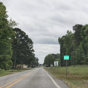 Two-lane rural road with Lono sign and other road signs on its right side