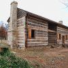 Wood cabin building on dirt with stone chimney