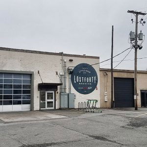 Brick building with garage bay door and "Lost Forty Brewing" logo painted on the wall