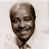 African-American man with mustache smiling in suit and tie