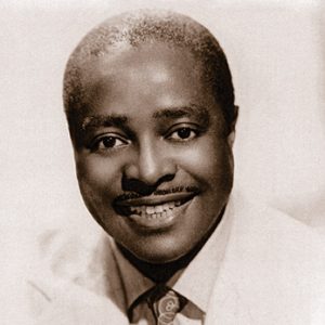 African-American man with mustache smiling in suit and tie