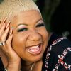 African-American woman with short hair smiling with her head resting in her hand