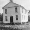 Two-story building with white siding and cupola