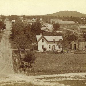 Houses and town buildings on dirt roads with hill in the background