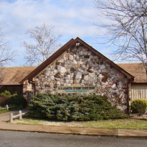 Wood and stone building with sign and walking path to the entrance