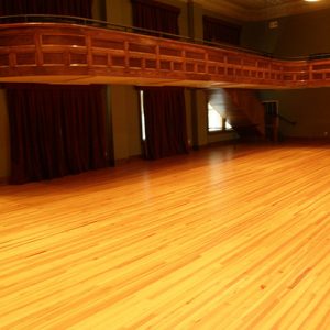 Ballroom with waxed wood floor and balcony with red curtains