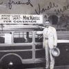 White man in suit with hat posing with a wood paneled car which has a sign on its roof "Vote for James Uncle Mac MacKrell for Governor"