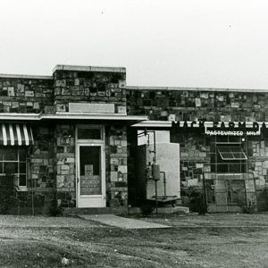 Car parked outside single-story building with stone walls