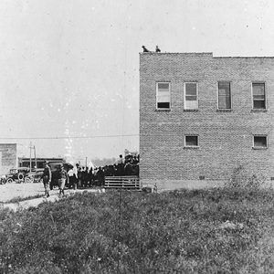 Soldiers and others outside and on rooftop of multistory building