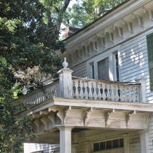 Balcony on two-story house with nearby tree