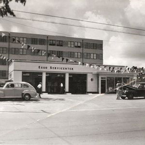 Service station with cars "Esso Service center" with larger multistory building in background