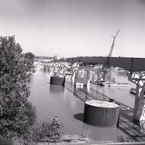 Concrete bridge over river under construction with crane barges