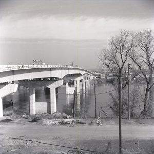 Concrete and steel bridge over river with cranes on platform