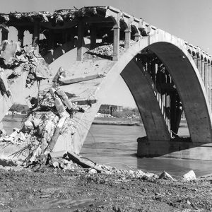 Demolished section of concrete arch bridge over river