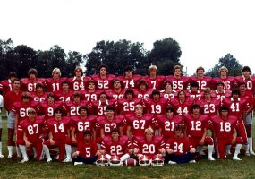 Group of young men in red football uniforms and their coaches