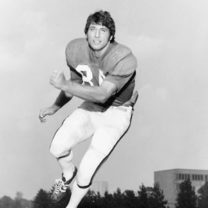 White man in football uniform running on field