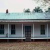 Single-story house with weathered metal roof and covered porch on front and side