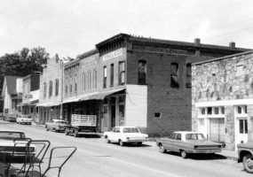 Street lined with brick and buildings and parked cars