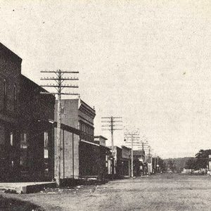 Looking down dirt street with brick buildings on both sides