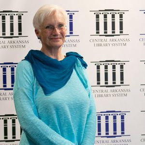 white woman with white hair wearing glasses in blue shirt and pants