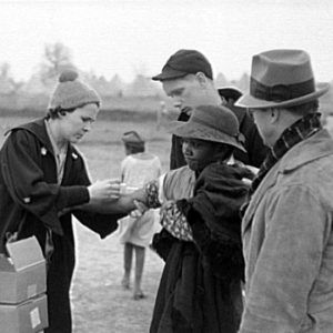 African-American woman receiving a shot from a white woman with people around her