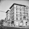 Multistory hotel building with covered walkway on city street next to  parking lot