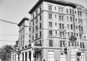 Multistory hotel building with covered walkway on city street next to  parking lot