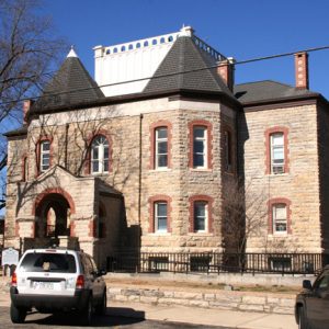 two story stone building with cars parked in front