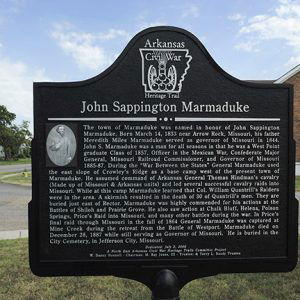 "John Sappington Marmaduke" historical marker sign on street corner with brick building behind it