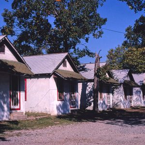 Row of identical single-story housing units on gravel road