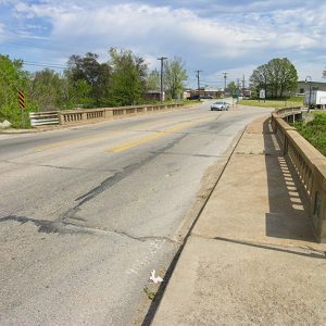 Looking across concrete bridge over creek on two-lane street