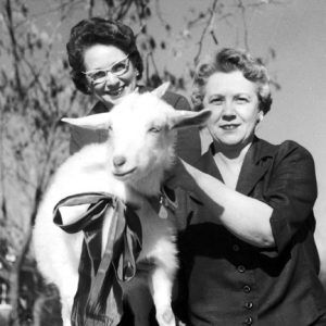 Two older white women posing with a goat