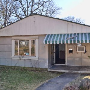 one-story house with green and white metal awning over porch