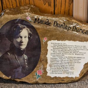 Portrait of white woman with necklace and text on rock face labeled "Maude Dunlap Duncan"