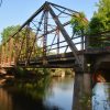 Close-up of steel truss bridge over river with concrete columns