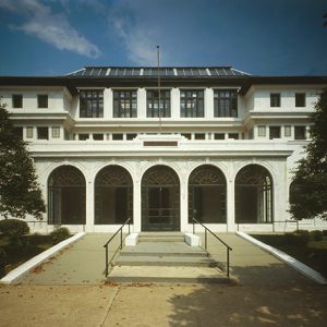 Symmetrical three-story building with ramps and arched front windows