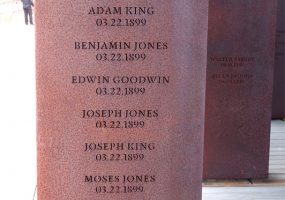 Rust-colored metal rectangle engraved with names and locations