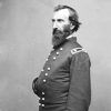 white man with beard posing with one hand inside his military jacket