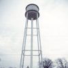 Buildings and water tower inside fence on street