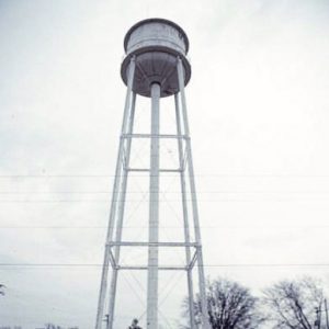 Buildings and water tower inside fence on street