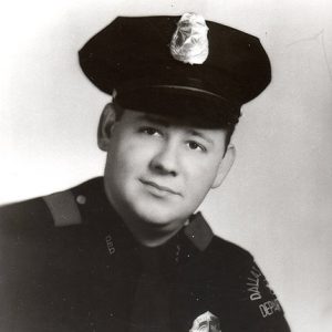 dark-eyed white man in police uniform with cap and badge