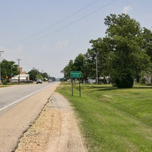 Street with green "McDougal" sign and green trees and grass