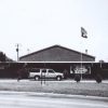 Chevrolet Suburban parked at brick armory building with flag poles and a sign saying "join our team"