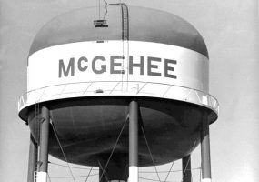 top of massive water tower with seven legs ladders and surrounding walkway painted "McGehee" in large letters.