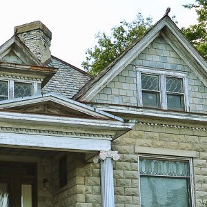 Bedroom window and gabled roof with chimney of two-story brick house