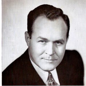 White man in suit and tie with State Seal on campaign flyer