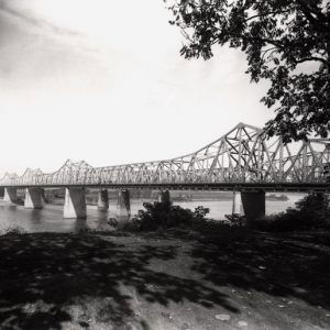 steel bridge crossing river with river bank in foreground