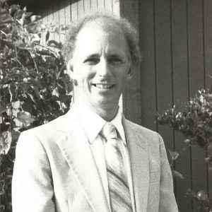 White man standing in suit and tie standing outside building