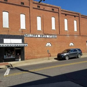 Side view of two-story "Miller's Drug Store" on street